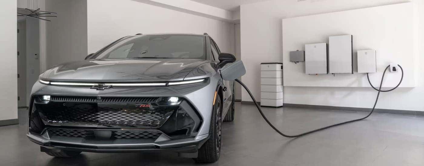Silver 2025 Chevy Equinox EV charging in a garage.