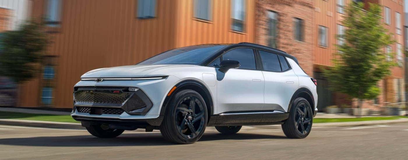 White 2025 Chevy Equinox EV for sale driving down a road.