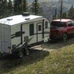 A red 2025 Ford Maverick towing a trailer to a Ford service center near Covington.