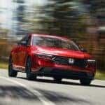 Red 2025 Honda Accord Sport L Hybrid driving around a bend.