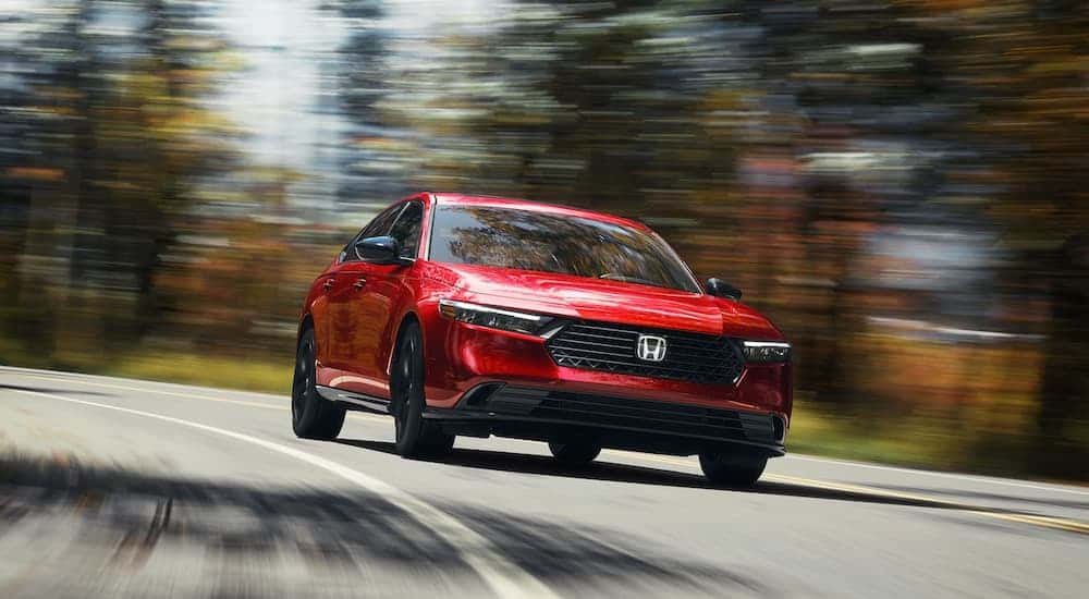 Red 2025 Honda Accord Sport L Hybrid driving around a bend.