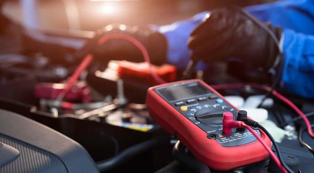 A technician checking voltage on a car battery.