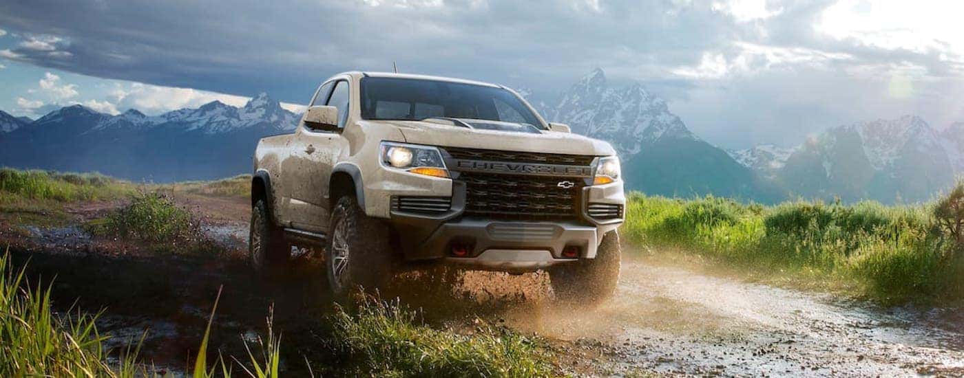 Tan 2021 Chevy Colorado ZR2 driving down a dirt hill after visiting a dealer with used trucks for sale near Florence.