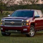 A red 2014 Chevy Silverado 1500 parked on grass.