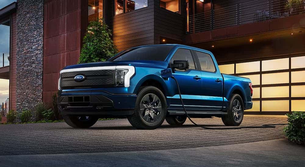A blue 2022 Ford F-150 Lightning charging after viewing used trucks for sale near Florence.