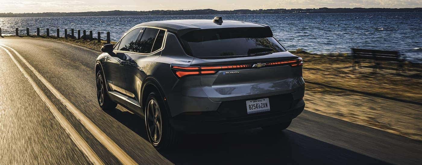 Rear of a black 2026 Chevy Equinox EV driving down a road.