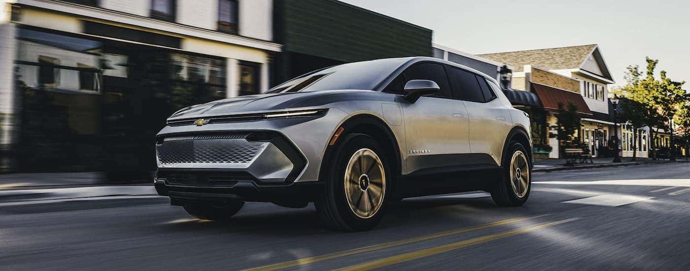 Silver 2026 Chevy Equinox EV for sale in Cincinnati driving through a town.
