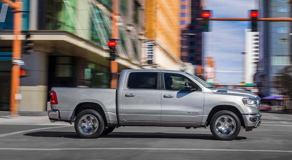 Side of a silver 2019 Ram 1500 driving through an intersection.