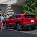 A person walks away from a red 2026 Chevy Trax parked on the curb.