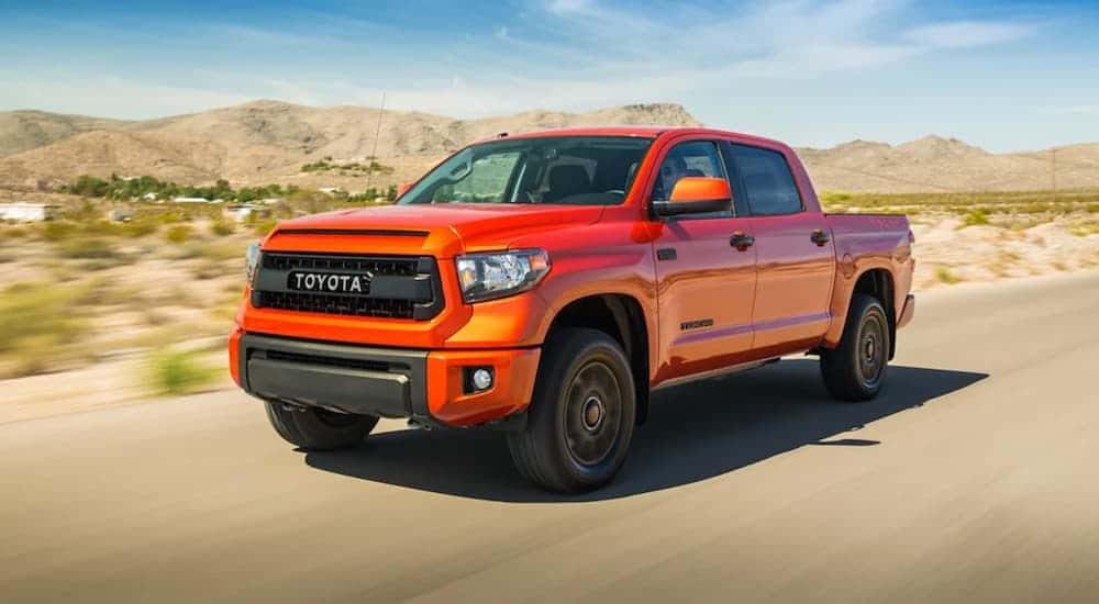 Orange 2015 Toyota Tundra driving down the street to a Toyota service center near Mason.