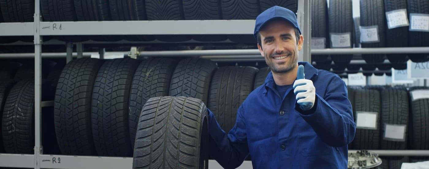 A technician holding a tire and giving a thumbs up.