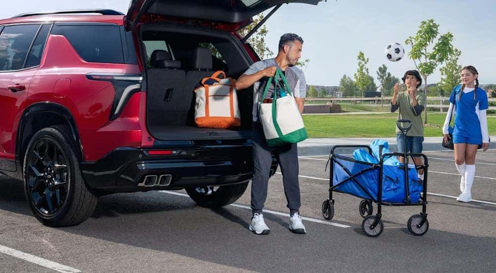 A family loads bags into the trunk of a 2024 Chevy Traverse RS