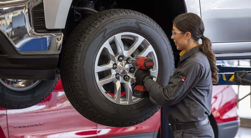 A person changes a tire on a Chevy vehicle