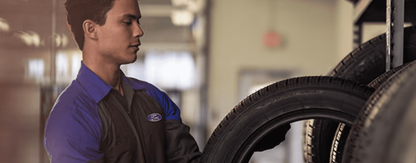 A Ford employee pulls a new set of tires of the rack