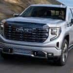 A silver 2024 GMC Sierra 1500 driving to a GMC service center near Monroe.