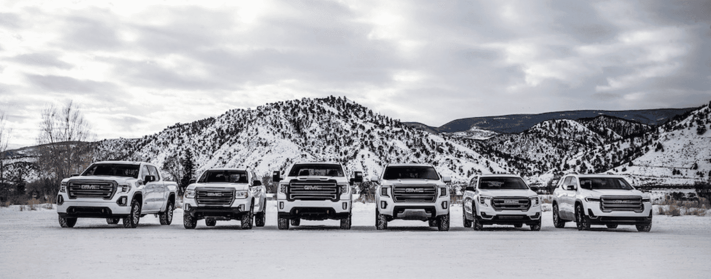 White 2021 GMC AT4 lineup parked in front of a snowy mountain