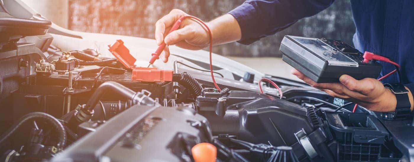 A person checks the battery terminals on a GMC vehicle