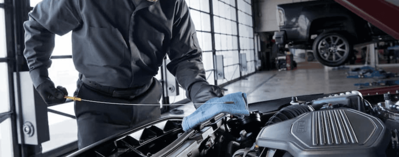 A mechanic checks the oil dipstick in a GMC service center near Monroe