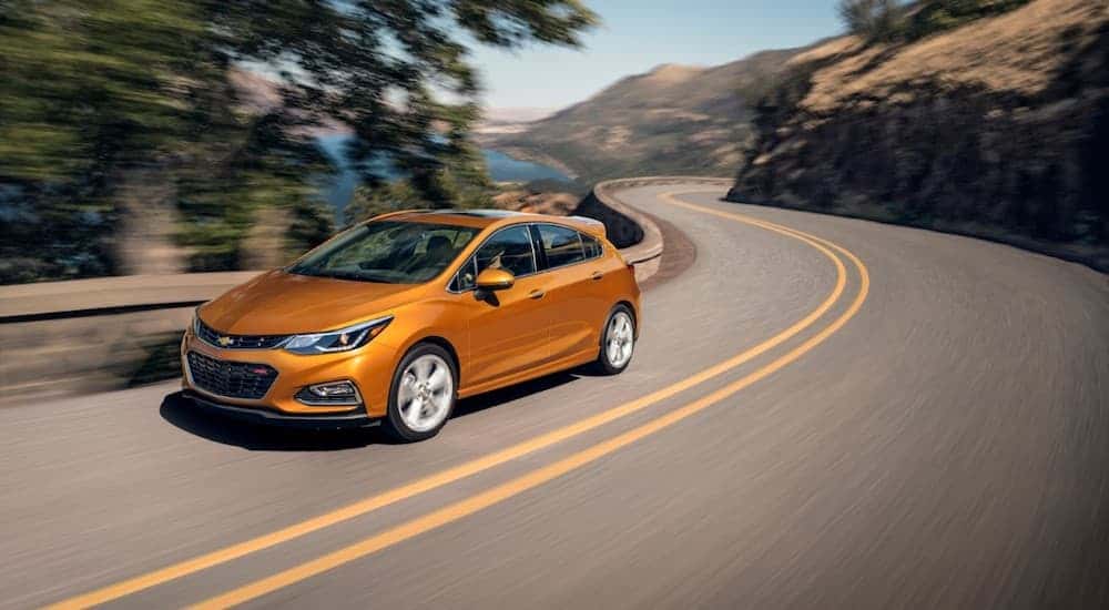 An orange 2018 Chevy Cruze driving to view a used Chevy for sale in Cincinnati.