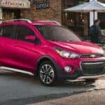 A pink 2020 Chevy Spark parked in a city.