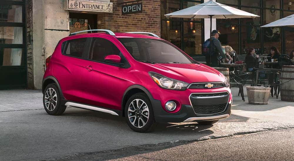 A pink 2020 Chevy Spark parked in a city.