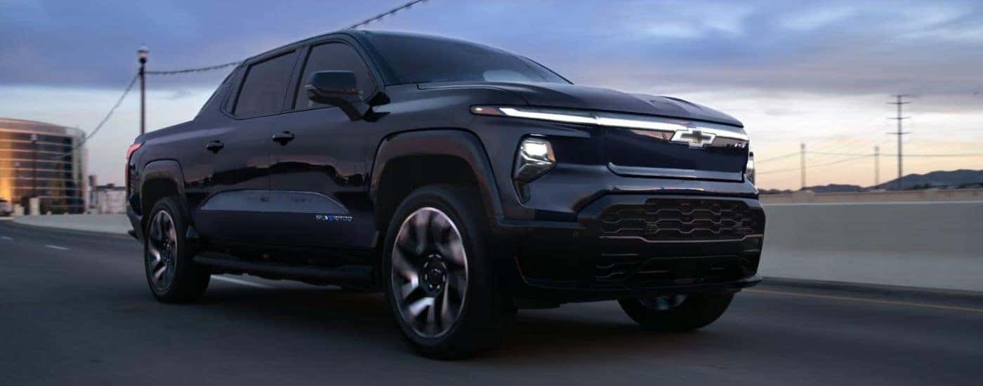 Black 2025 Chevy Silverado EV RST driving at dusk