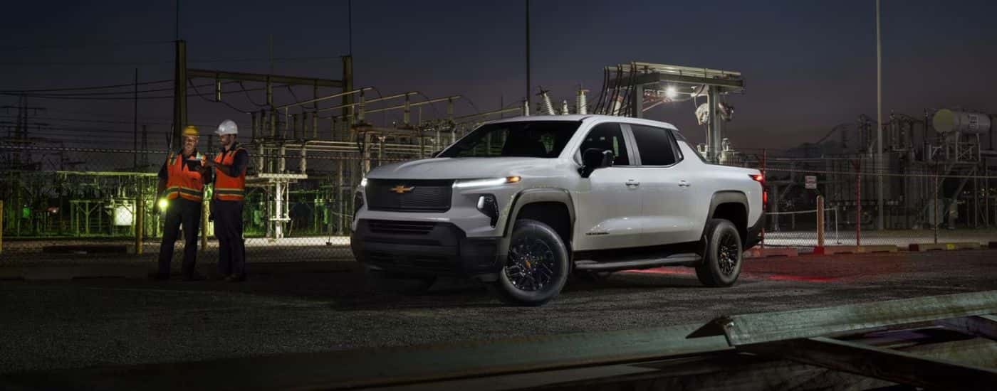 White 2026 Chevy Silverado EV WT parked near a power substation