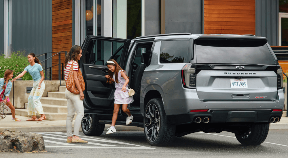 A family getting out of a silver 2026 Chevy Suburban RST