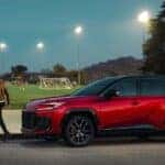 A red 2026 Toyota RAV4 Hybrid parked near a soccer field.