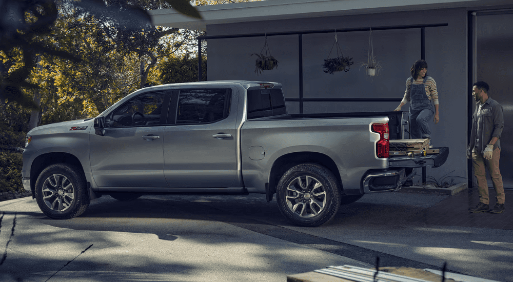 A couple unloading the bed of their silver 2026 Chevy SIlverado 1500 after purchasing a work truck for sale