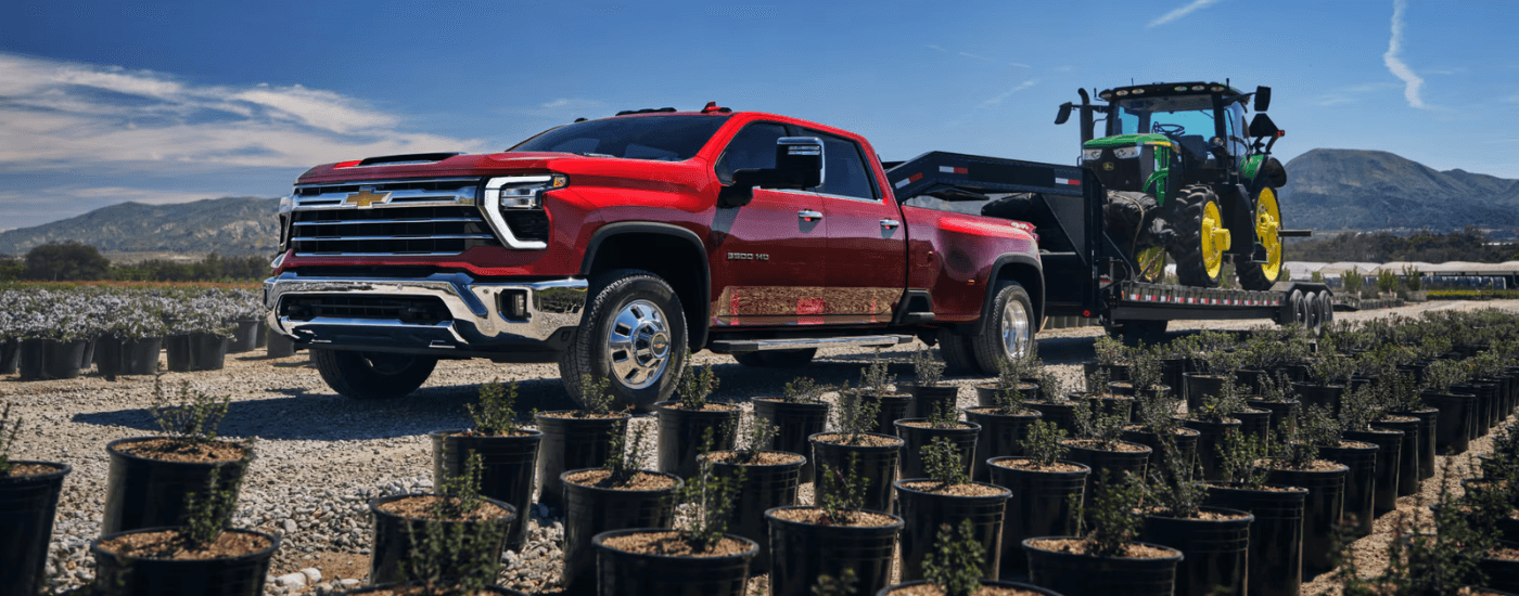 Red 2026 Chevy Silverado 3500 HD towing a tractor