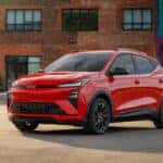 Red 2027 Chevy Bolt RS parked in front of a brick building
