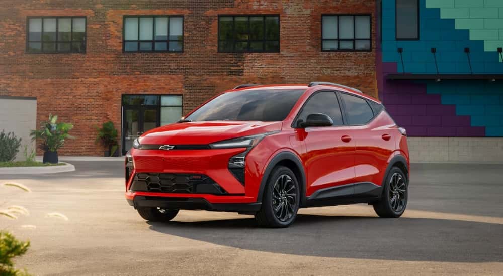 Red 2027 Chevy Bolt RS parked in front of a brick building