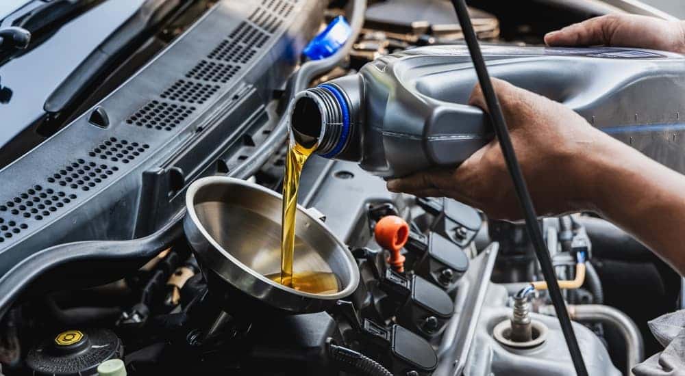 Oil can being poured into a funnel during an oil change near monroe.
