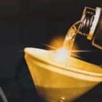 Close-up of an oil can being poured into a funnel.