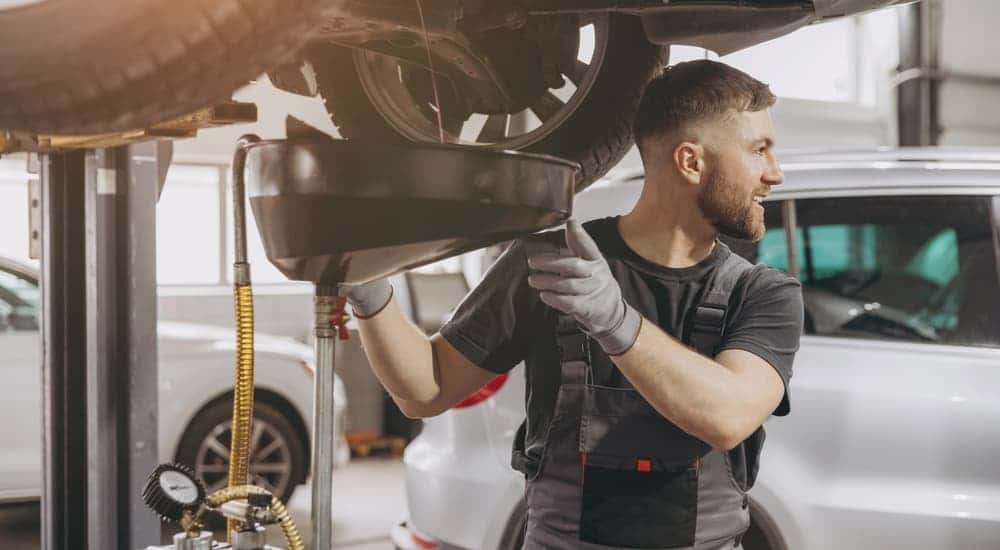 Mechanic draining oil from a vehicle.