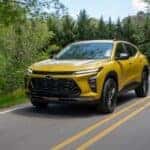 A yellow 2024 Chevy Trax ACTIV driving to view a used Chevy for sale near Loveland.