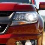 Close-up on the headlight of a red 2015 Chevy Colorado.