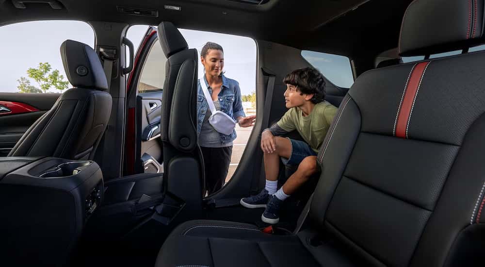 Interior view of a 2026 Chevy Traverse with a child sitting in a passenger seat as a woman opens a door.