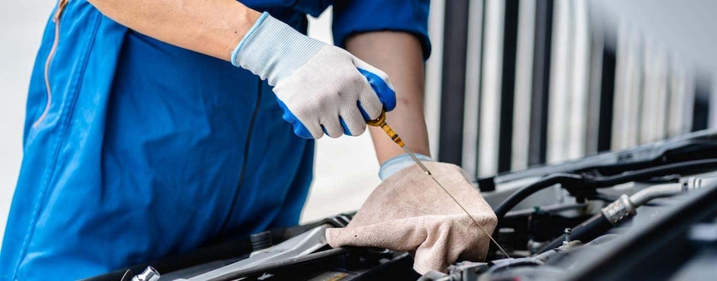 Mechanic using an oil dipstick near an engine during an oil change near Finneytown.
