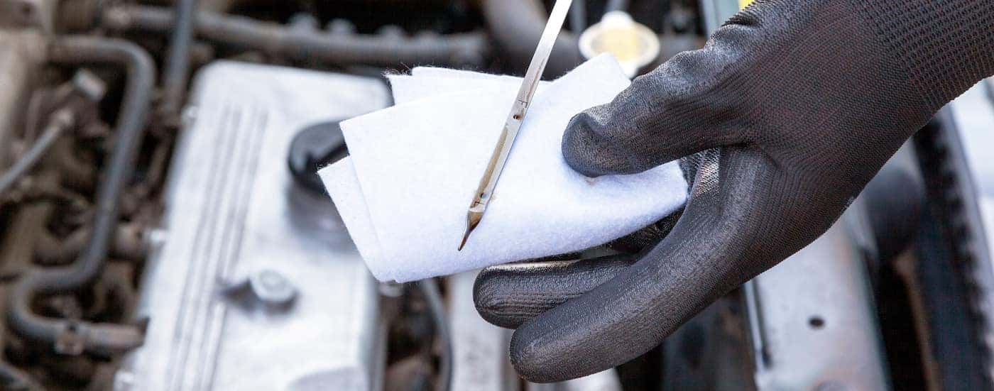 Close-up of a mechanic wiping an oil dipstick.