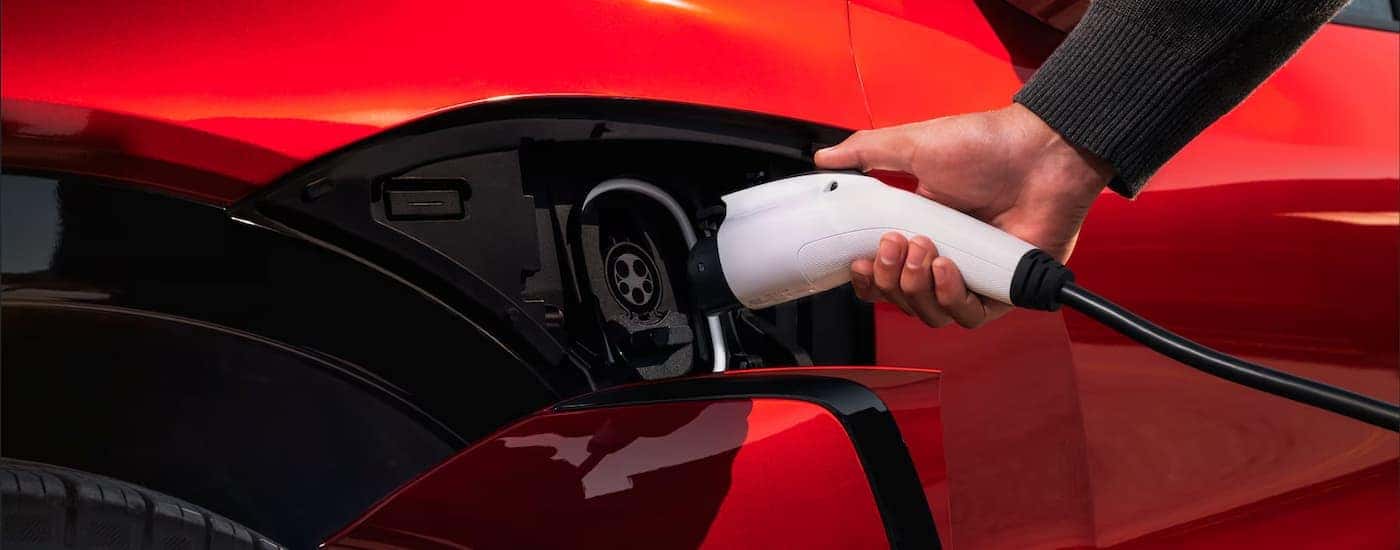 A man plugging in a red 2026 Chevy Blazer EV to charge