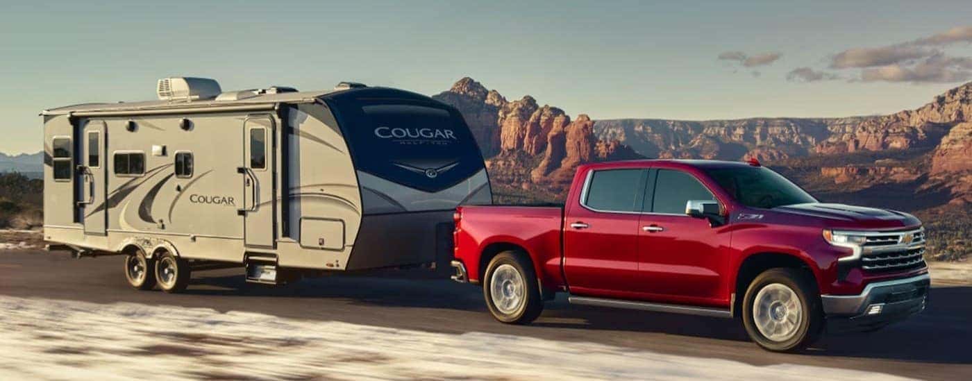 A red 2026 Chevy Silverado 1500 towing a trailer/