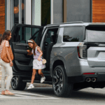 A family getting out of a silver 2026 Chevy Suburban RST
