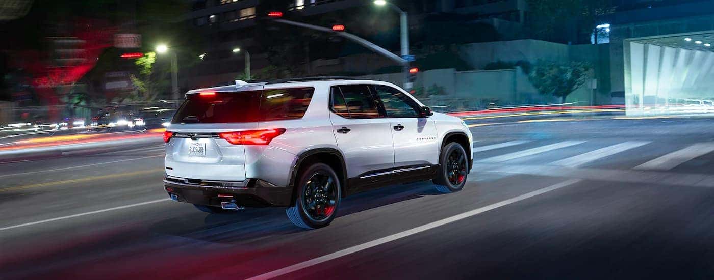 White 2023 Chevy Traverse driving down a city street