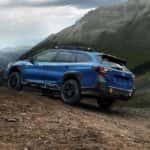 A blue 2023 Subaru Outback Wilderness off-roading on a trail