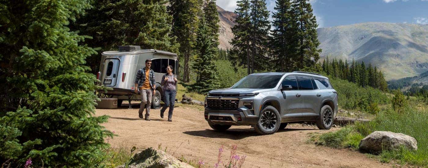 Silver 2026 Chevy Traverse parked off-road near a camp.