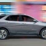 A silver 2023 Chevy Equinox driving in a city.