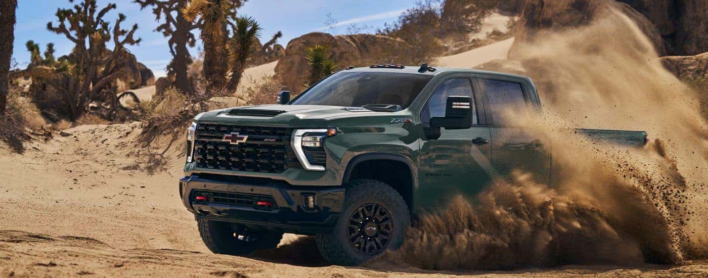 A green 2026 Chevy Silverado 2500 HD ZR2 kicking up dust in a desert.