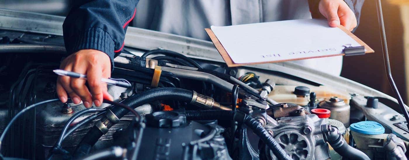 Service technician going over the engine compartment while holding a clipboard